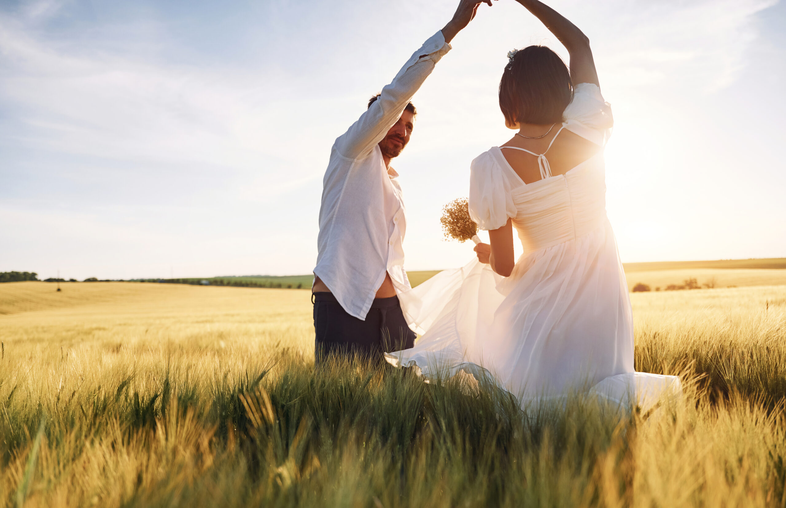 Against beautiful sunlight. Couple just married. Together on the majestic agricultural field.