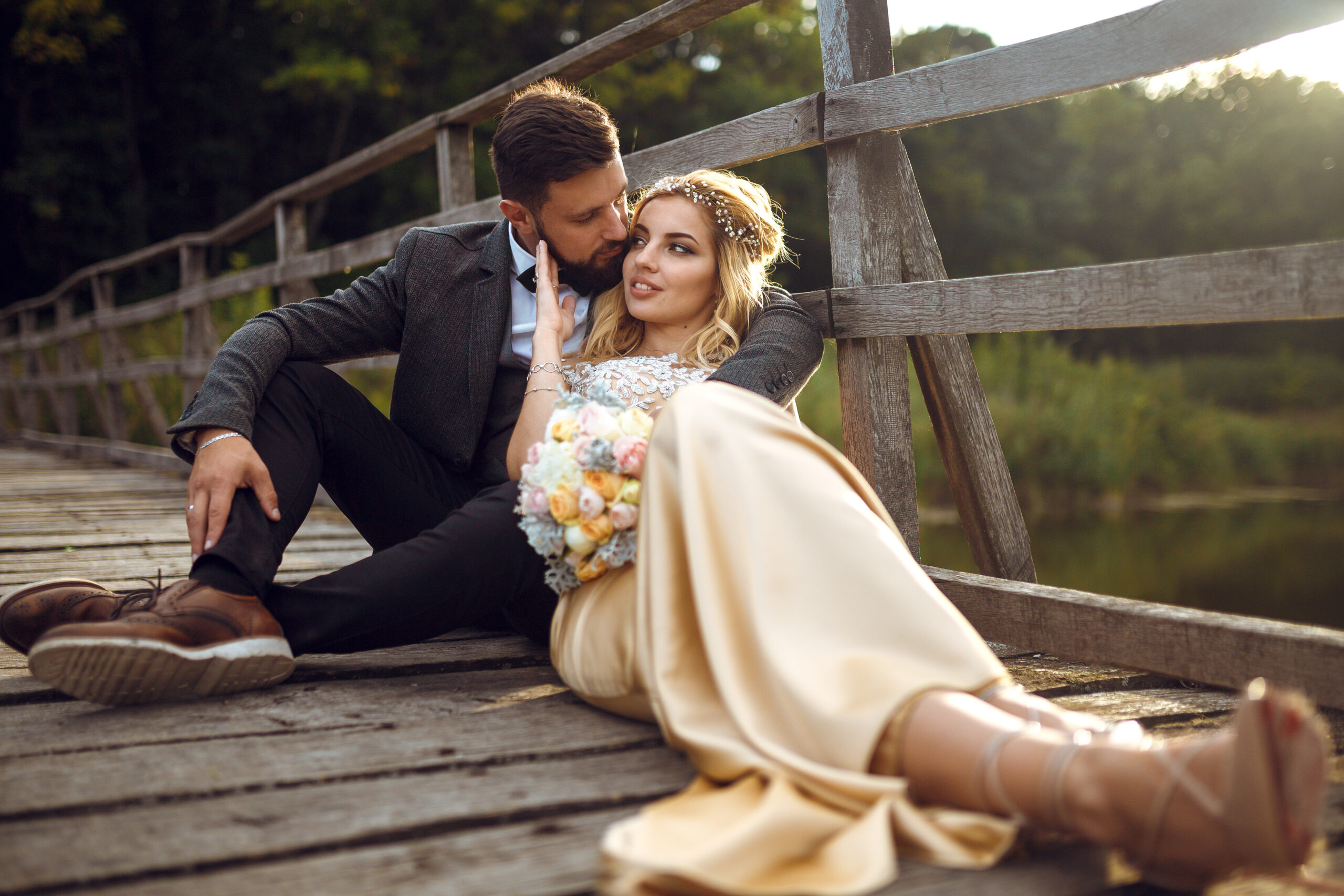 Stylish couple of happy newlyweds posing in the park on their wedding day.. Sexy kissing stylish couple.